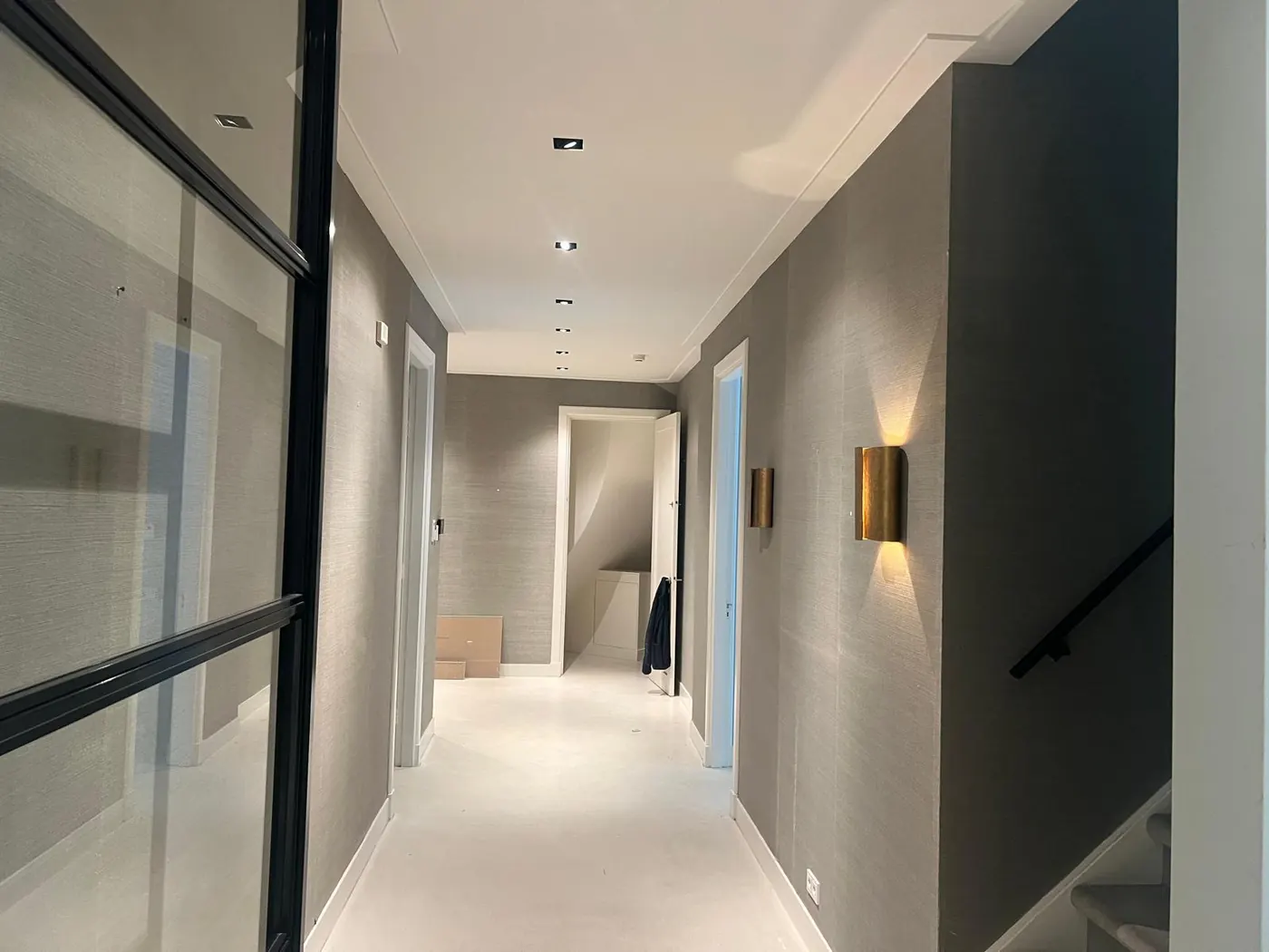 Hal met stalen deur en wandverlichting